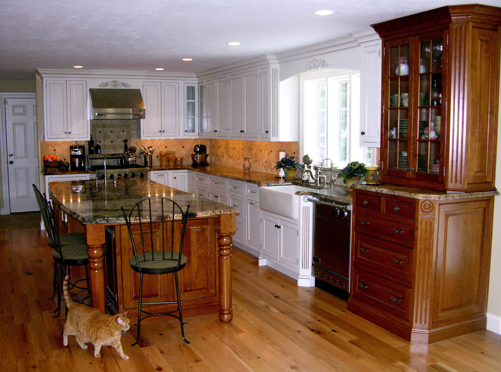 Inredning av ett klassiskt stort kök, med luckor med profilerade fronter, vita skåp, en köksö, en rustik diskho, granitbänkskiva, flerfärgad stänkskydd, stänkskydd i stenkakel, rostfria vitvaror och ljust trägolv