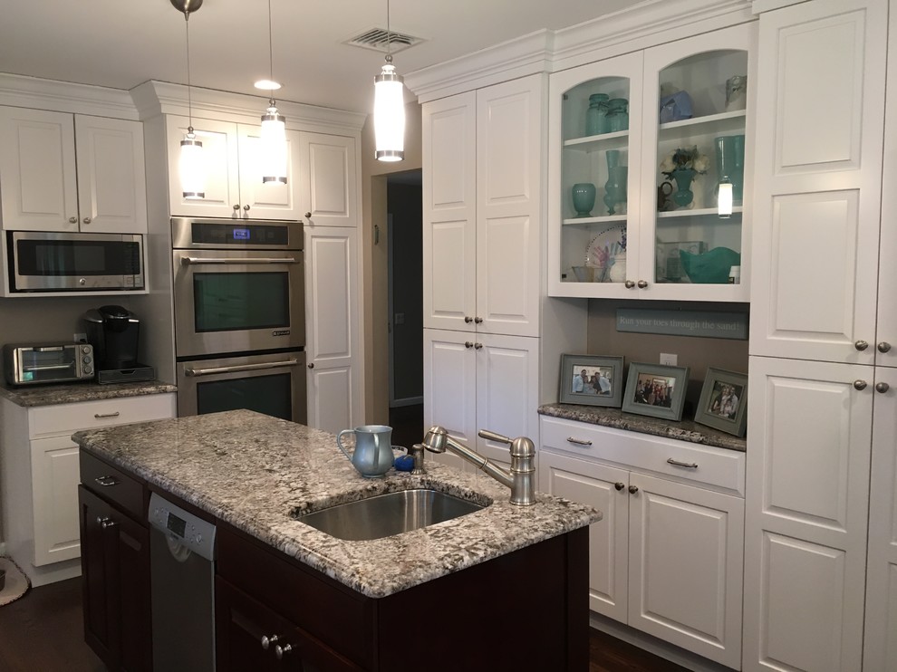 Exempel på ett mellanstort klassiskt kök, med luckor med upphöjd panel, vita skåp, granitbänkskiva, rostfria vitvaror, en köksö, beige stänkskydd, stänkskydd i keramik, en undermonterad diskho, mörkt trägolv och brunt golv