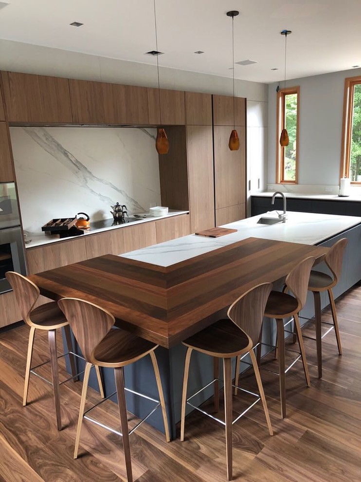 Photo of an expansive modern l-shaped kitchen in New York with a submerged sink, flat-panel cabinets, blue cabinets, engineered stone countertops, multi-coloured splashback, stone slab splashback, coloured appliances, medium hardwood flooring, an island, brown floors and multicoloured worktops.
