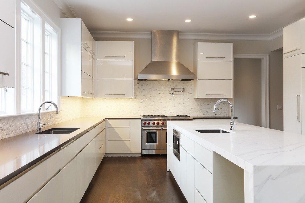 Large contemporary u-shaped kitchen/diner in New York with a submerged sink, flat-panel cabinets, white cabinets, white splashback, integrated appliances, dark hardwood flooring, an island, brown floors, composite countertops and stone tiled splashback.
