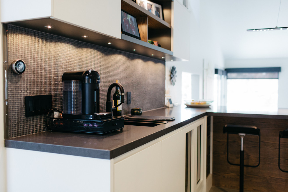 This is an example of a medium sized modern u-shaped open plan kitchen in Salt Lake City with a double-bowl sink, flat-panel cabinets, white cabinets, brown splashback, mosaic tiled splashback, black appliances, ceramic flooring and an island.