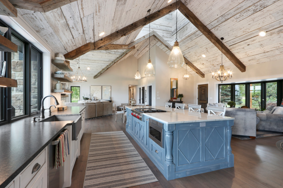 Bild på ett lantligt kök, med släta luckor, granitbänkskiva, rostfria vitvaror, mörkt trägolv, en köksö och grått golv