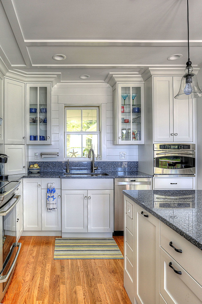 Immagine di un cucina con isola centrale costiero con lavello sottopiano, ante in stile shaker, ante bianche, elettrodomestici in acciaio inossidabile, pavimento in legno massello medio e top blu