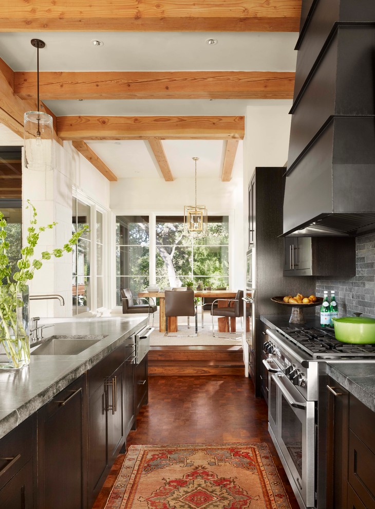 Bild på ett medelhavsstil kök, med en undermonterad diskho, skåp i shakerstil, skåp i mörkt trä, grått stänkskydd, rostfria vitvaror, en köksö och stänkskydd i skiffer