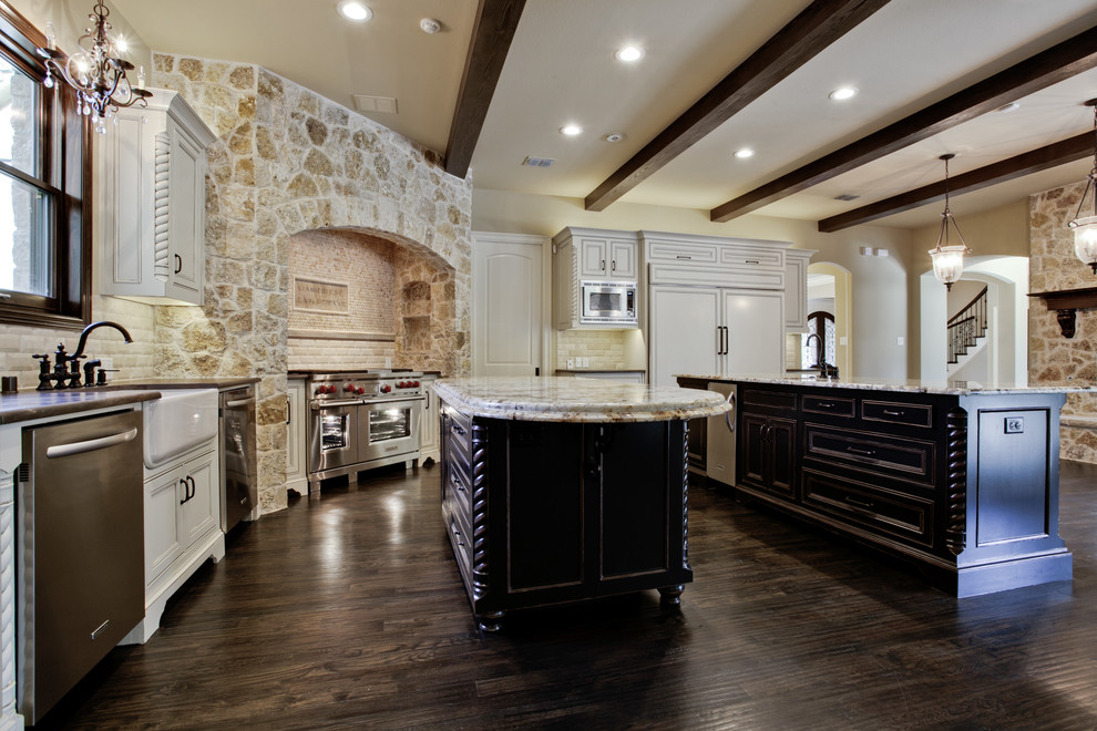 Kitchen - mediterranean dark wood floor kitchen idea in Dallas with a drop-in sink, raised-panel cabinets, white cabinets, solid surface countertops, multicolored backsplash, stone slab backsplash, stainless steel appliances and an island