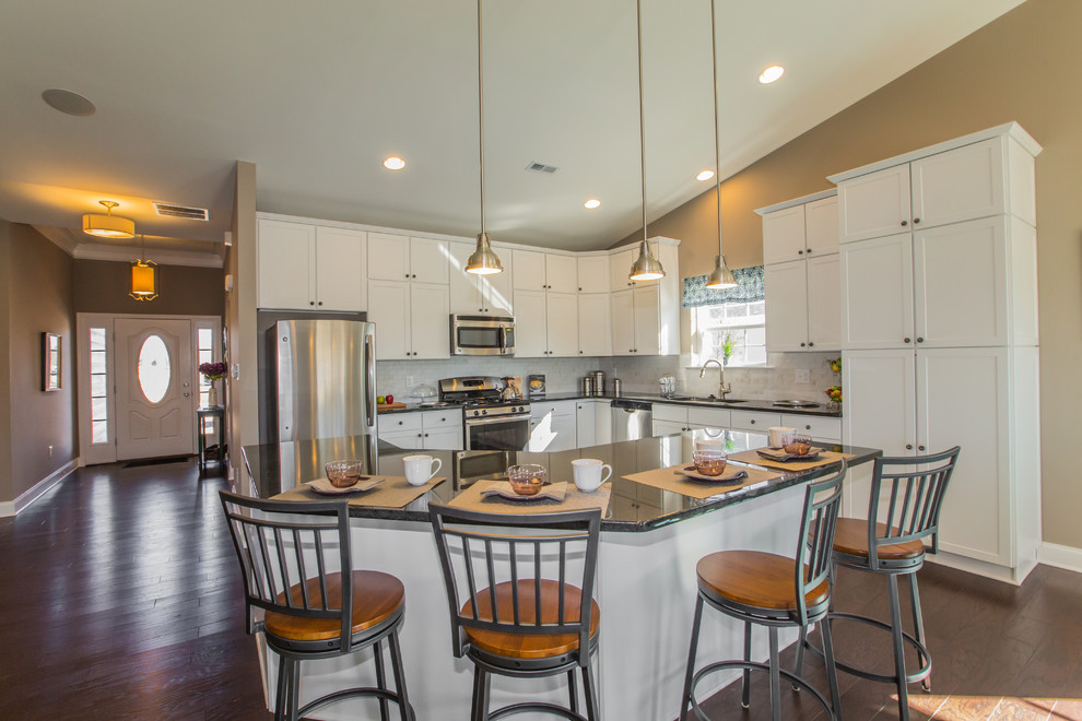 Mid-sized transitional l-shaped dark wood floor eat-in kitchen photo in Philadelphia with shaker cabinets, white cabinets, granite countertops, white backsplash, porcelain backsplash, stainless steel appliances, an island and an undermount sink