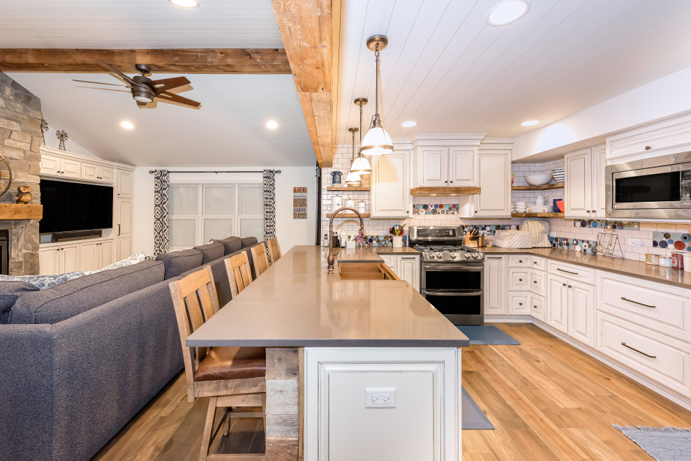 Example of a mid-sized mountain style u-shaped laminate floor and brown floor eat-in kitchen design in Chicago with a farmhouse sink, raised-panel cabinets, white cabinets, quartz countertops, white backsplash, ceramic backsplash, stainless steel appliances, a peninsula and gray countertops