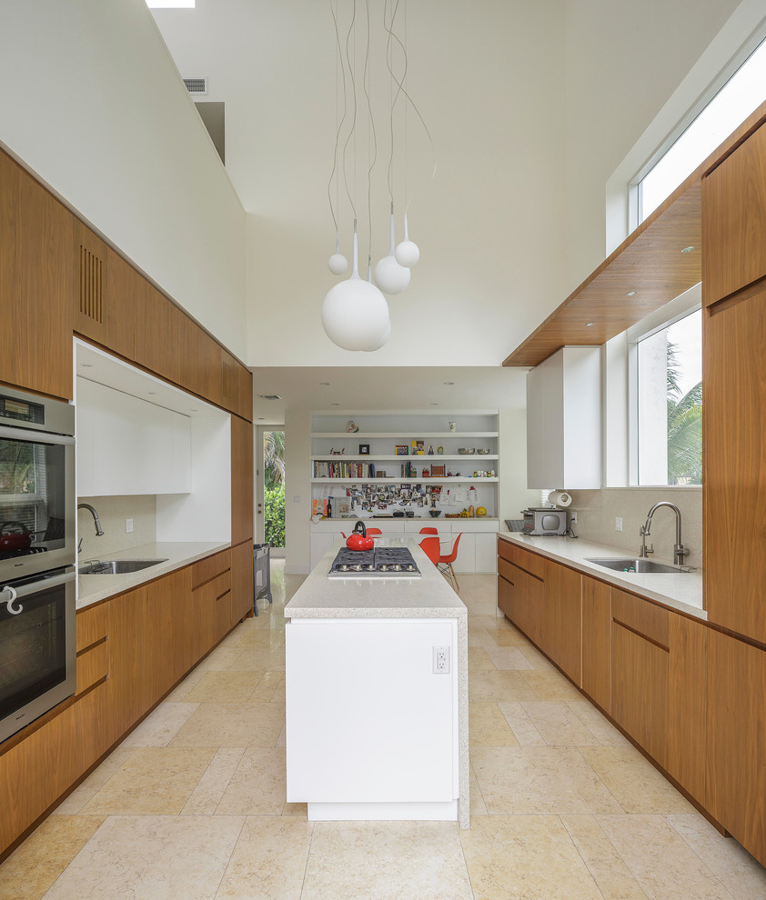 Ejemplo de cocina comedor minimalista con armarios con paneles lisos, puertas de armario de madera oscura, salpicadero beige y electrodomésticos de acero inoxidable