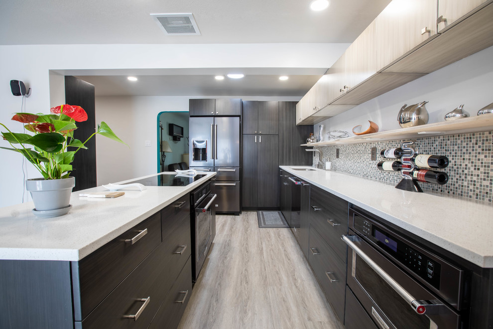 Mid-sized minimalist l-shaped vinyl floor and gray floor open concept kitchen photo in Albuquerque with a drop-in sink, flat-panel cabinets, dark wood cabinets, quartz countertops, multicolored backsplash, ceramic backsplash, stainless steel appliances, an island and white countertops