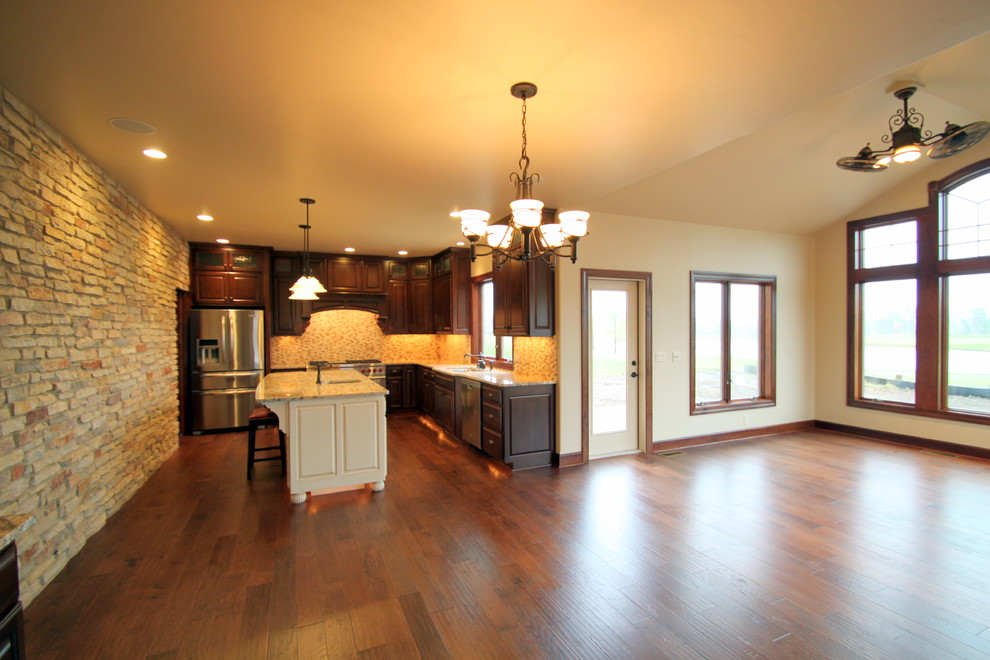 Example of a classic l-shaped dark wood floor open concept kitchen design in Milwaukee with raised-panel cabinets, dark wood cabinets, granite countertops, multicolored backsplash, mosaic tile backsplash, stainless steel appliances and an island