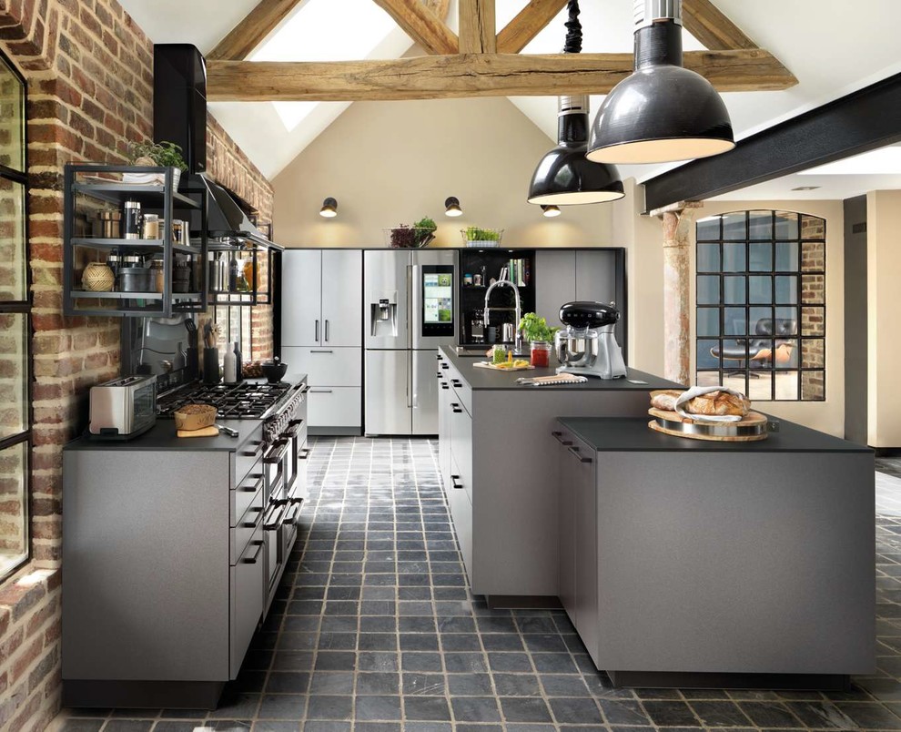Idee per una cucina industriale con ante lisce, ante grigie, elettrodomestici in acciaio inossidabile, pavimento grigio e top nero