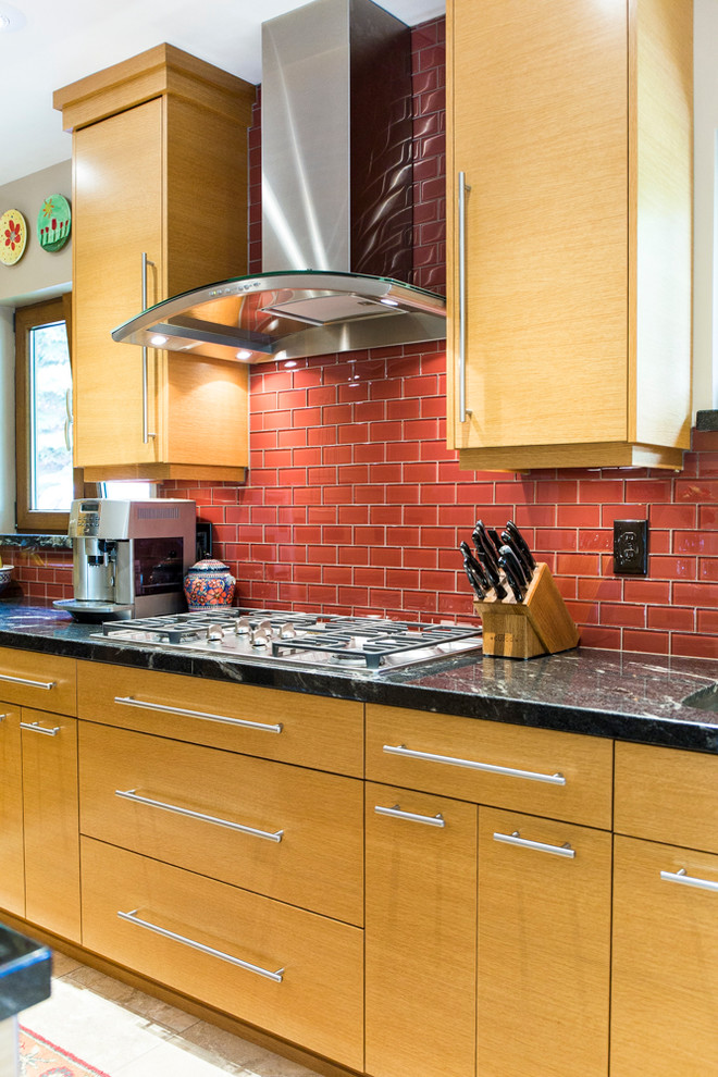 Пример оригинального дизайна: большая п-образная кухня в современном стиле с светлыми деревянными фасадами, красным фартуком, фартуком из стеклянной плитки, техникой из нержавеющей стали и островом