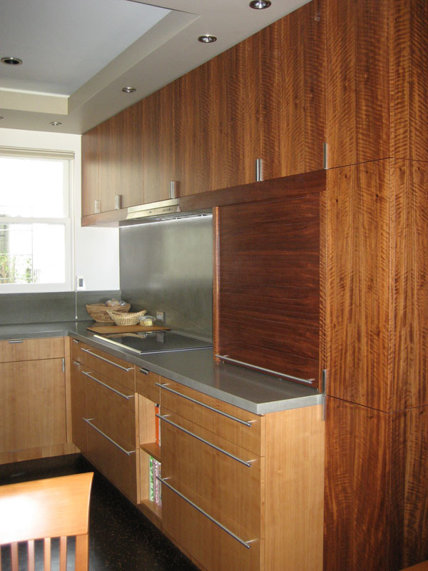 Example of a small minimalist l-shaped medium tone wood floor eat-in kitchen design in San Francisco with an undermount sink, flat-panel cabinets, dark wood cabinets, concrete countertops, gray backsplash, stainless steel appliances and an island