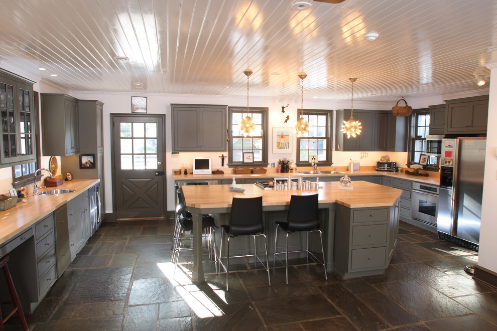 Photo of a rural kitchen in Philadelphia with flat-panel cabinets, stainless steel appliances, wood worktops and slate flooring.