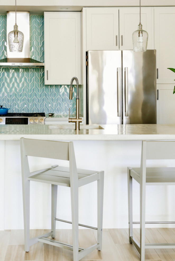 Foto på ett vit kök med öppen planlösning, med skåp i shakerstil, vita skåp, bänkskiva i betong, rostfria vitvaror, en köksö, blått stänkskydd och stänkskydd i mosaik