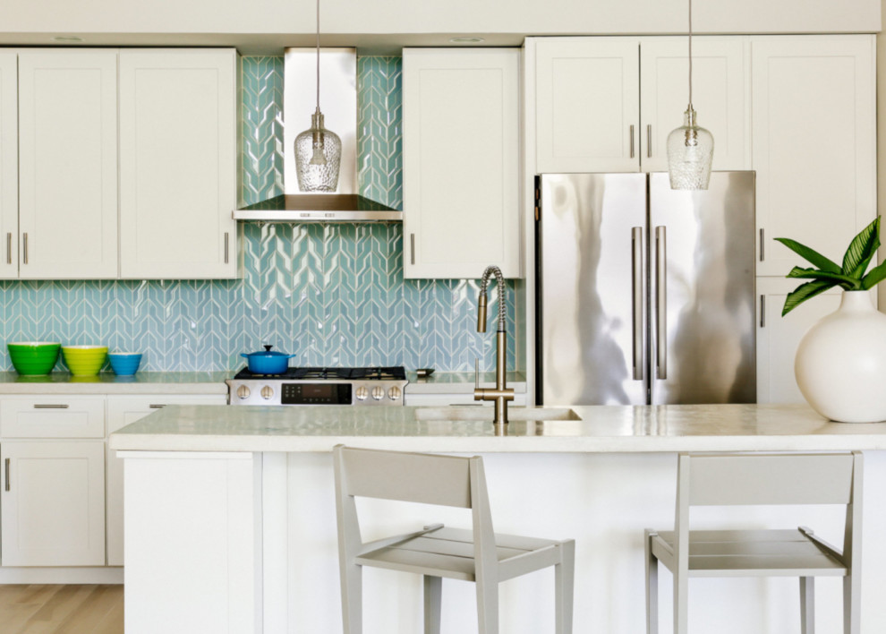 Inspiration för vitt kök med öppen planlösning, med skåp i shakerstil, vita skåp, bänkskiva i betong, blått stänkskydd, stänkskydd i mosaik, rostfria vitvaror och en köksö