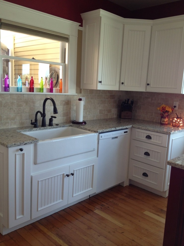 Exempel på ett avskilt, litet lantligt u-kök, med en rustik diskho, granitbänkskiva, beige stänkskydd, stänkskydd i tunnelbanekakel, vita vitvaror, mellanmörkt trägolv, en köksö, vita skåp och luckor med infälld panel