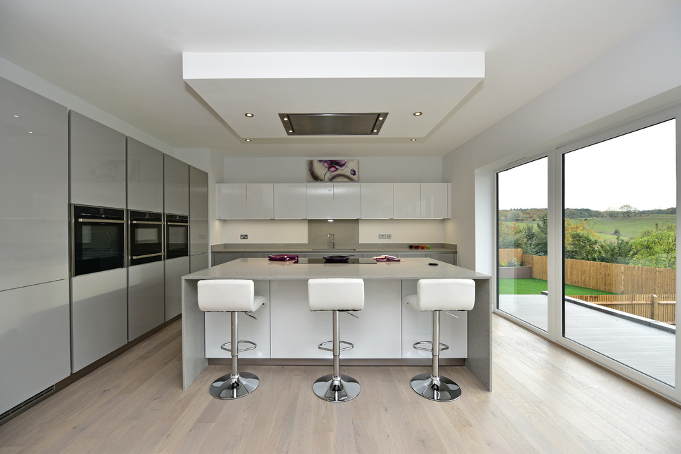 This is an example of a large contemporary kitchen in London with quartz worktops and black appliances.