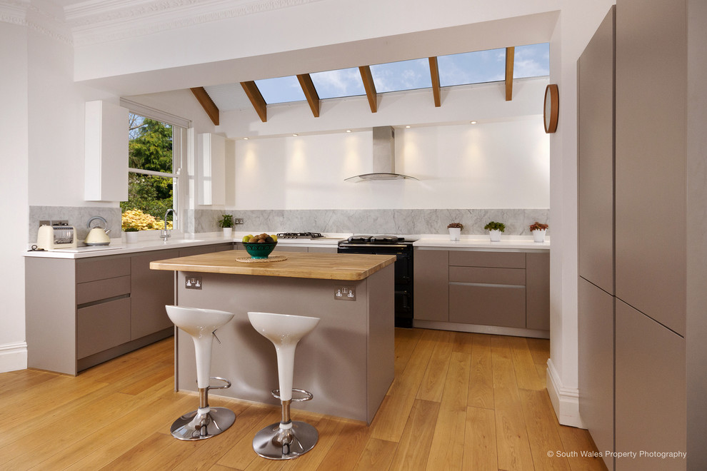 Idéer för ett mellanstort modernt vit kök, med en köksö, en integrerad diskho, släta luckor, beige skåp, bänkskiva i koppar, grått stänkskydd, stänkskydd i marmor, svarta vitvaror, mellanmörkt trägolv och brunt golv