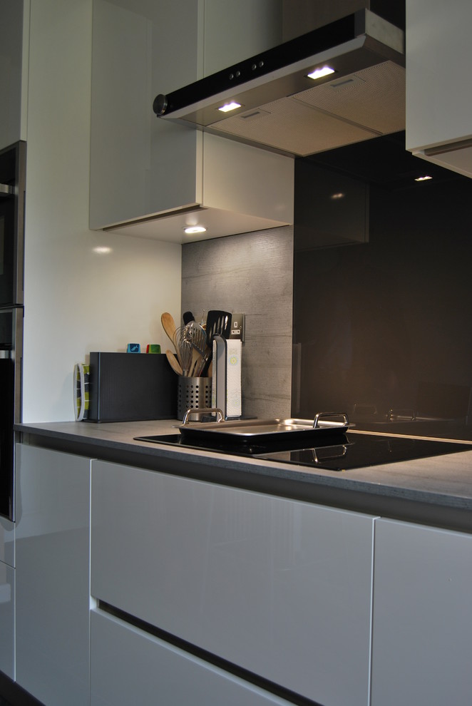 Immagine di una piccola cucina ad U design chiusa con ante bianche, top in laminato, nessuna isola, ante lisce e paraspruzzi grigio