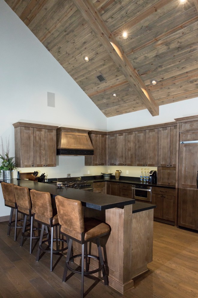 Inspiration for a large rustic u-shaped medium tone wood floor and brown floor open concept kitchen remodel in Phoenix with an undermount sink, shaker cabinets, medium tone wood cabinets, solid surface countertops, paneled appliances, no island and black countertops