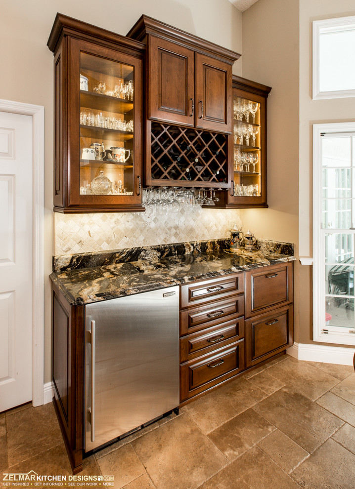 Example of a large classic u-shaped travertine floor eat-in kitchen design in Orlando with an undermount sink, raised-panel cabinets, medium tone wood cabinets, granite countertops, beige backsplash, stone tile backsplash and an island