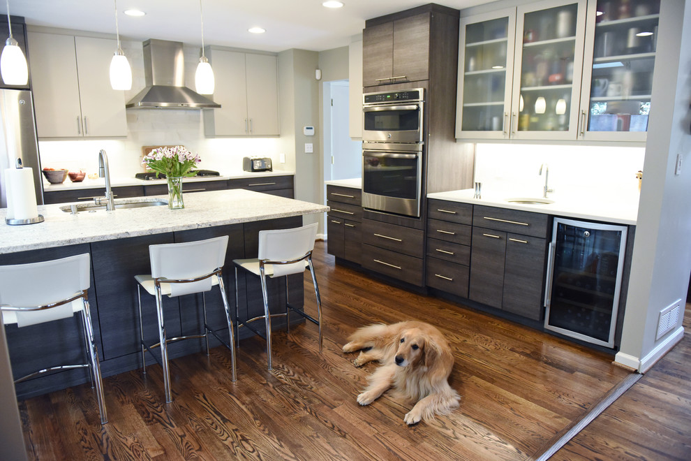 Mid-sized minimalist l-shaped medium tone wood floor and brown floor eat-in kitchen photo in Atlanta with an undermount sink, flat-panel cabinets, dark wood cabinets, granite countertops, white backsplash, marble backsplash, stainless steel appliances and an island