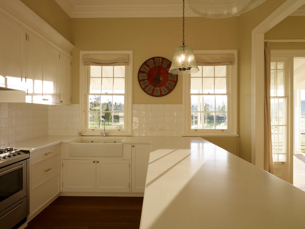 Eat-in kitchen - mid-sized farmhouse u-shaped medium tone wood floor eat-in kitchen idea in Sydney with a farmhouse sink, recessed-panel cabinets, white cabinets, quartz countertops, white backsplash, ceramic backsplash, stainless steel appliances and no island