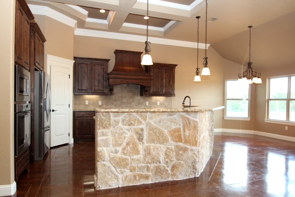 Bild på ett vintage l-kök, med en undermonterad diskho, luckor med upphöjd panel, skåp i mellenmörkt trä, granitbänkskiva, brunt stänkskydd, stänkskydd i stenkakel, rostfria vitvaror och betonggolv