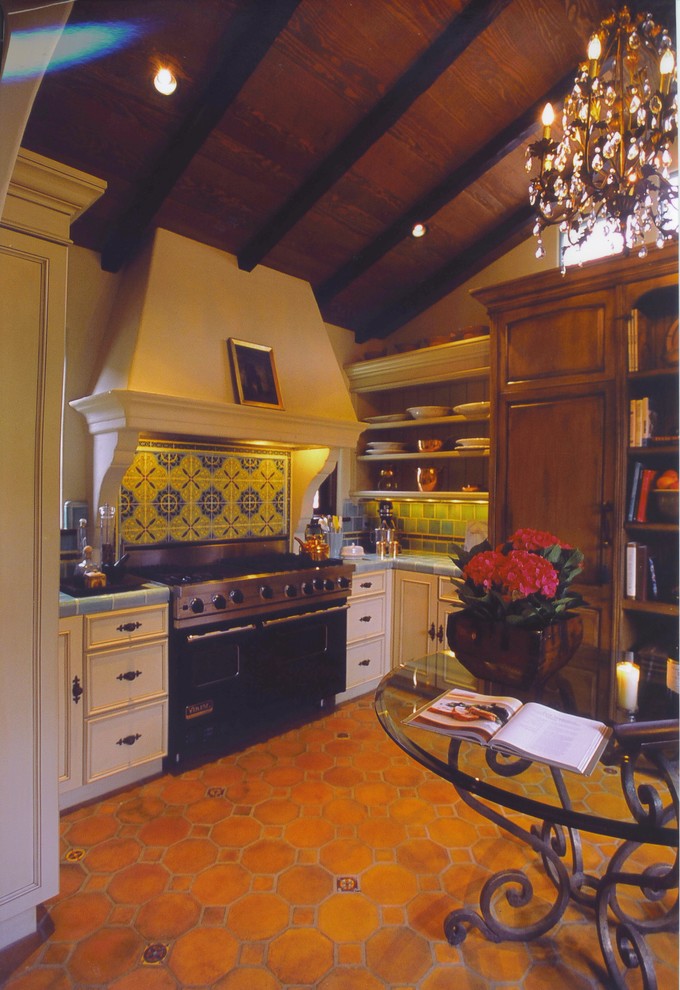 Exempel på ett avskilt, mellanstort klassiskt u-kök, med en dubbel diskho, skåp i slitet trä, kaklad bänkskiva, grönt stänkskydd, stänkskydd i keramik, rostfria vitvaror, klinkergolv i terrakotta och luckor med upphöjd panel
