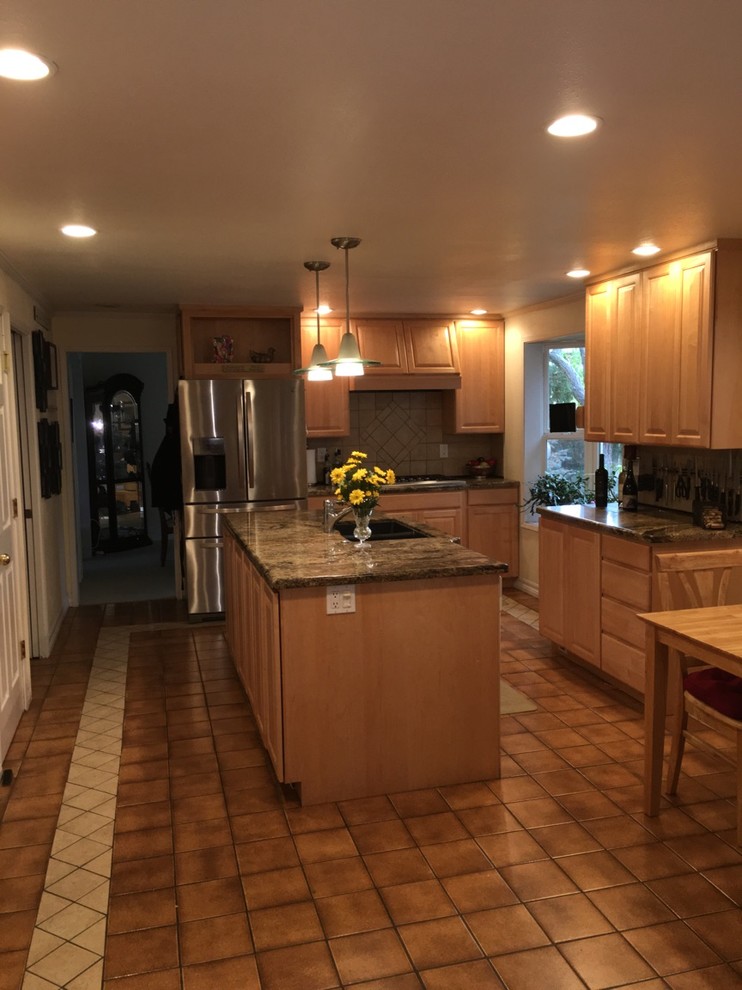 Klassisk inredning av ett mellanstort kök, med en undermonterad diskho, luckor med upphöjd panel, skåp i ljust trä, granitbänkskiva, brunt stänkskydd, stänkskydd i cementkakel, rostfria vitvaror, klinkergolv i keramik och en köksö