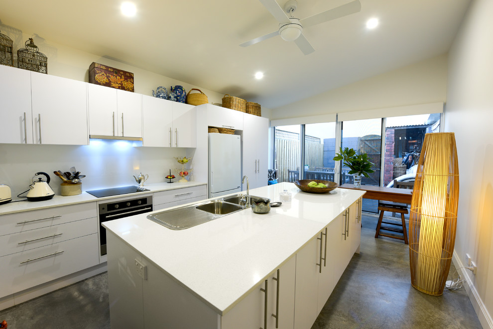 Exempel på ett litet klassiskt linjärt kök med öppen planlösning, med en dubbel diskho, släta luckor, vita skåp, bänkskiva i koppar, vitt stänkskydd, glaspanel som stänkskydd, rostfria vitvaror, betonggolv, en köksö och grått golv