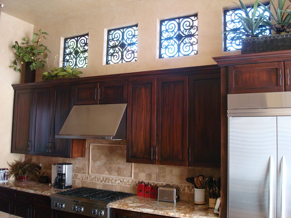 Exempel på ett mellanstort medelhavsstil kök, med en undermonterad diskho, skåp i shakerstil, skåp i mörkt trä, granitbänkskiva, beige stänkskydd, stänkskydd i stenkakel, rostfria vitvaror, klinkergolv i porslin och en köksö