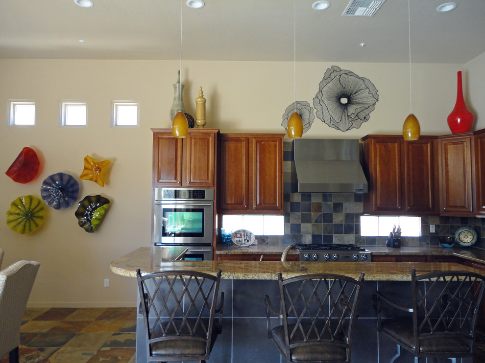 Inspiration for a large eclectic u-shaped slate floor eat-in kitchen remodel in Phoenix with an undermount sink, raised-panel cabinets, medium tone wood cabinets, granite countertops, multicolored backsplash and stainless steel appliances