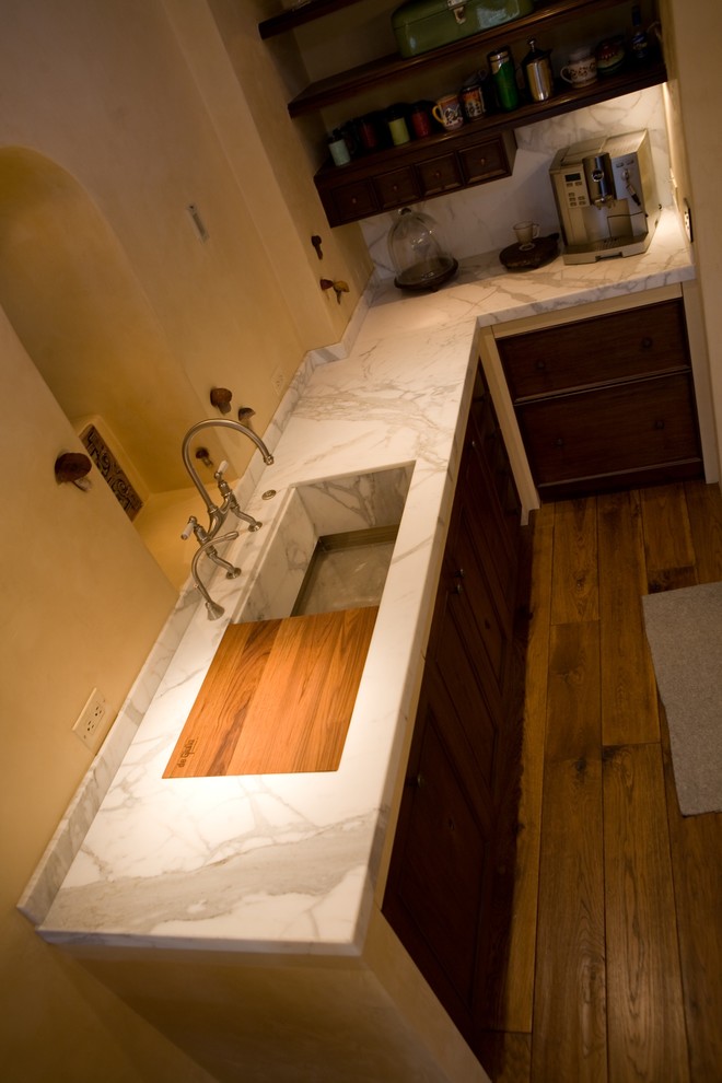 Foto på ett lantligt kök, med en integrerad diskho, luckor med infälld panel, skåp i mellenmörkt trä, marmorbänkskiva, flerfärgad stänkskydd, stänkskydd i sten, ljust trägolv och en köksö