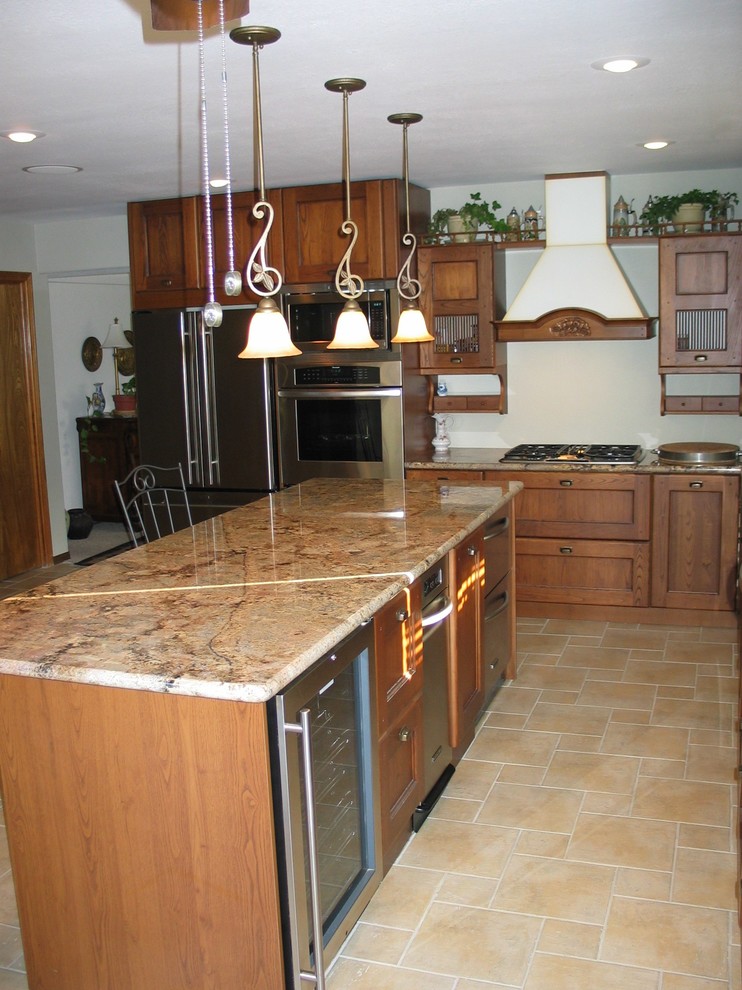 Esempio di una cucina classica di medie dimensioni con lavello sottopiano, ante con riquadro incassato, ante in legno scuro, top in granito, paraspruzzi bianco, elettrodomestici in acciaio inossidabile e pavimento in travertino