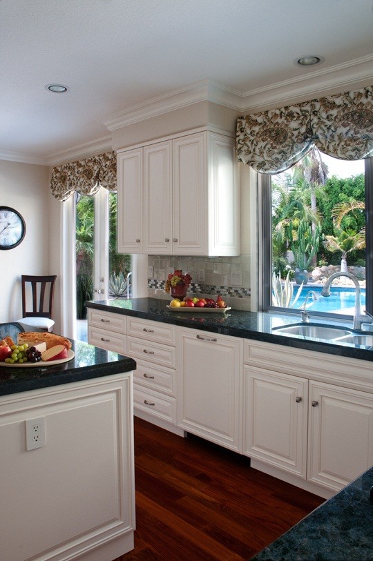 Mid-sized transitional u-shaped dark wood floor eat-in kitchen photo in San Diego with an undermount sink, raised-panel cabinets, white cabinets, granite countertops, beige backsplash, mosaic tile backsplash, paneled appliances and an island