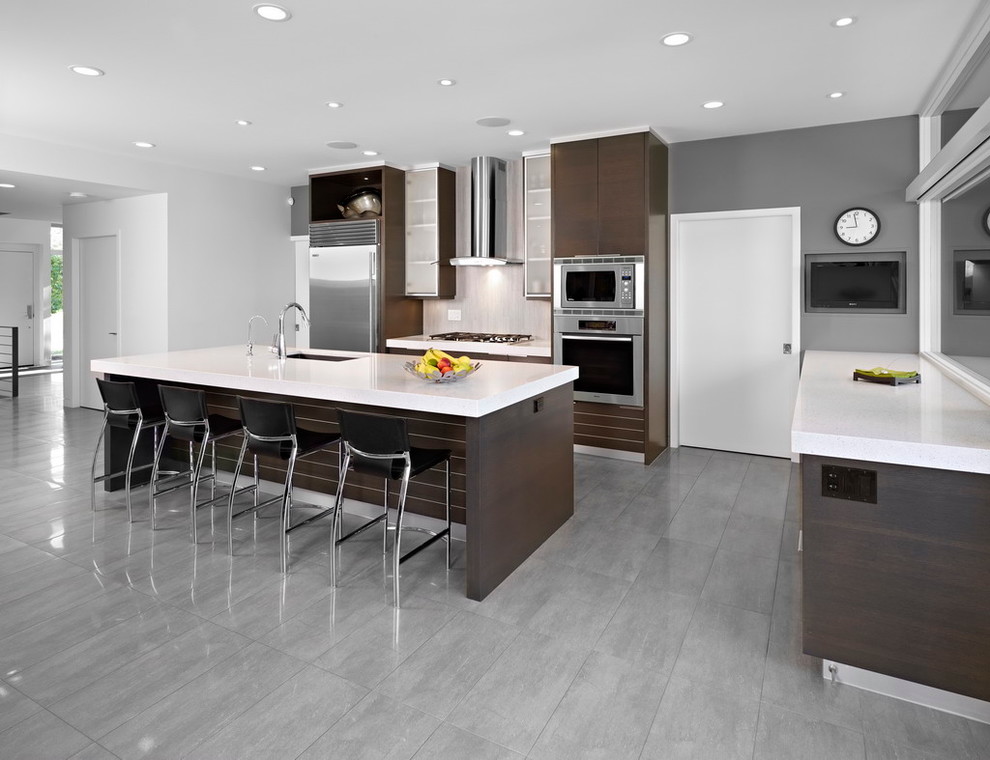 На фото: кухня в стиле модернизм с техникой из нержавеющей стали, серым полом и барной стойкой