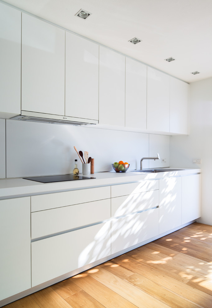 Immagine di una cucina lineare minimalista con ante lisce, ante bianche, pavimento in legno massello medio e nessuna isola