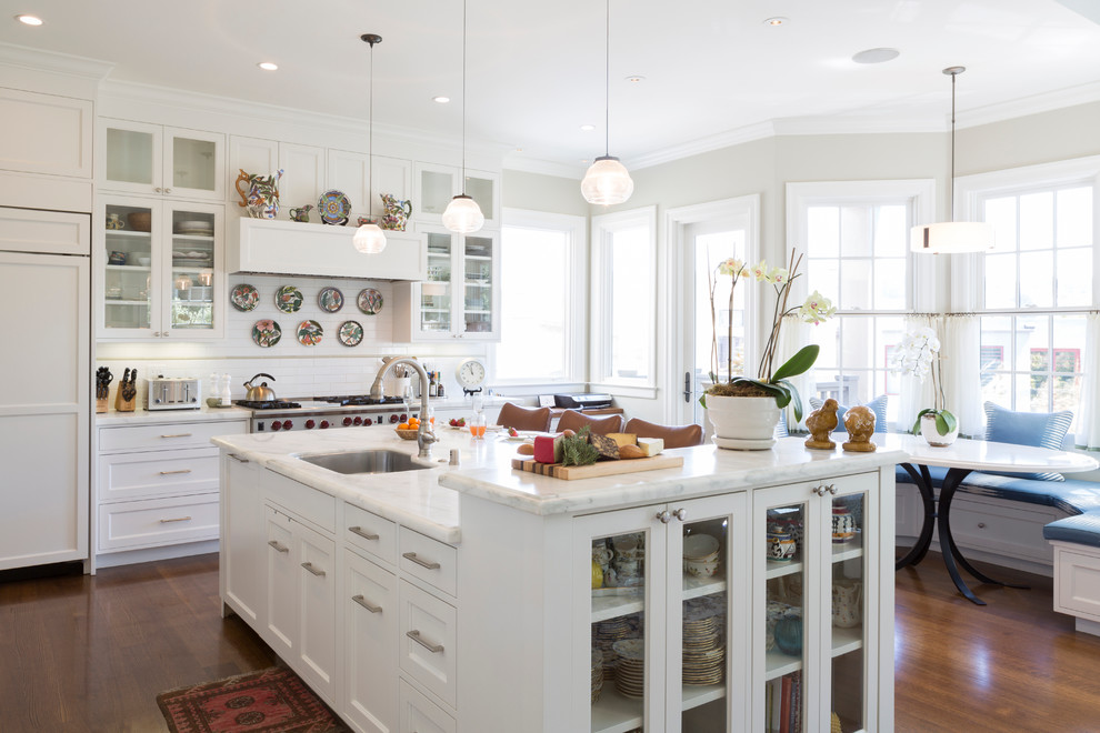 Klassische Wohnküche in L-Form mit Unterbauwaschbecken, Schrankfronten mit vertiefter Füllung, weißen Schränken, Küchenrückwand in Weiß, Elektrogeräten mit Frontblende, braunem Holzboden und Kücheninsel in San Francisco
