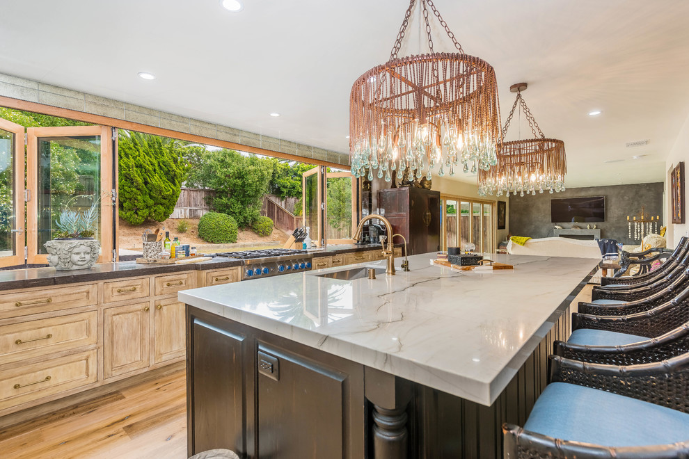 Example of a large island style l-shaped light wood floor and brown floor enclosed kitchen design in Orange County with an undermount sink, recessed-panel cabinets, light wood cabinets, marble countertops, metallic backsplash, mirror backsplash, paneled appliances, an island and gray countertops