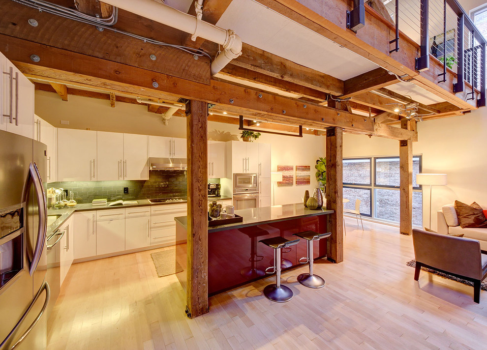 Источник вдохновения для домашнего уюта: угловая кухня-гостиная в современном стиле с плоскими фасадами, техникой из нержавеющей стали, белыми фасадами и зеленым фартуком