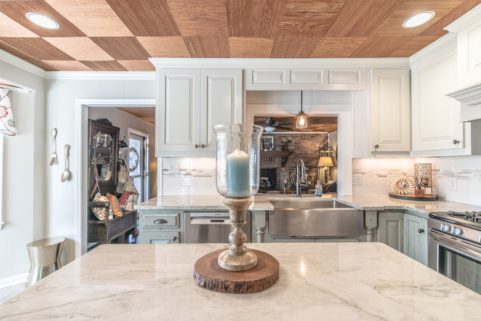 Mid-sized elegant l-shaped eat-in kitchen photo in Charleston with a farmhouse sink, quartzite countertops, white backsplash, porcelain backsplash, stainless steel appliances and an island