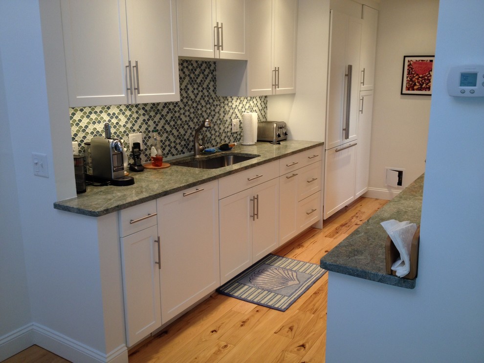 Idéer för att renovera ett avskilt, litet funkis u-kök, med en undermonterad diskho, skåp i shakerstil, vita skåp, laminatbänkskiva, grönt stänkskydd, stänkskydd i mosaik, integrerade vitvaror, mellanmörkt trägolv och brunt golv