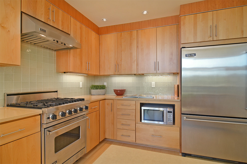 Example of a mid-sized trendy l-shaped light wood floor eat-in kitchen design in Seattle with an undermount sink, onyx countertops, glass tile backsplash, stainless steel appliances and an island