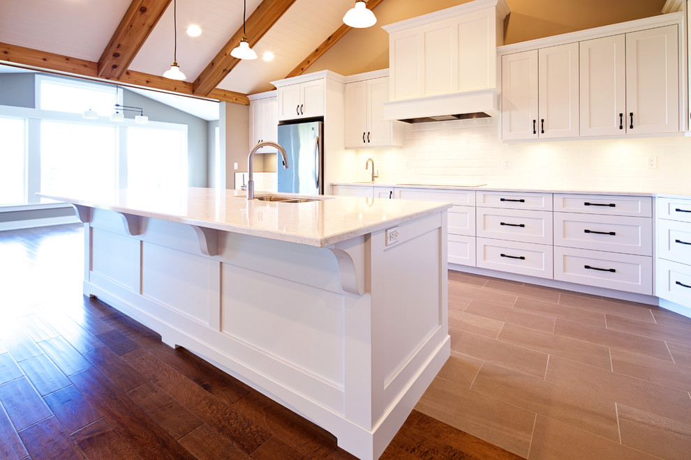 Design ideas for a large traditional l-shaped kitchen/diner in Vancouver with a double-bowl sink, shaker cabinets, white cabinets, quartz worktops, white splashback, ceramic splashback, stainless steel appliances, ceramic flooring and an island.