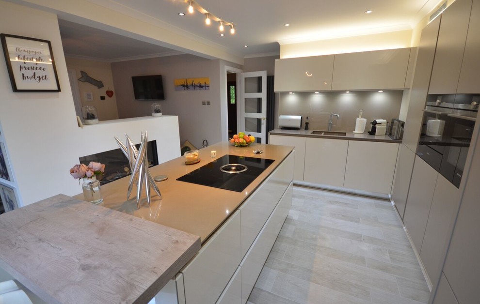 Medium sized contemporary galley kitchen/diner in Other with an integrated sink, recessed-panel cabinets, grey cabinets, integrated appliances, an island, granite worktops, white splashback, brick splashback, light hardwood flooring and grey floors.