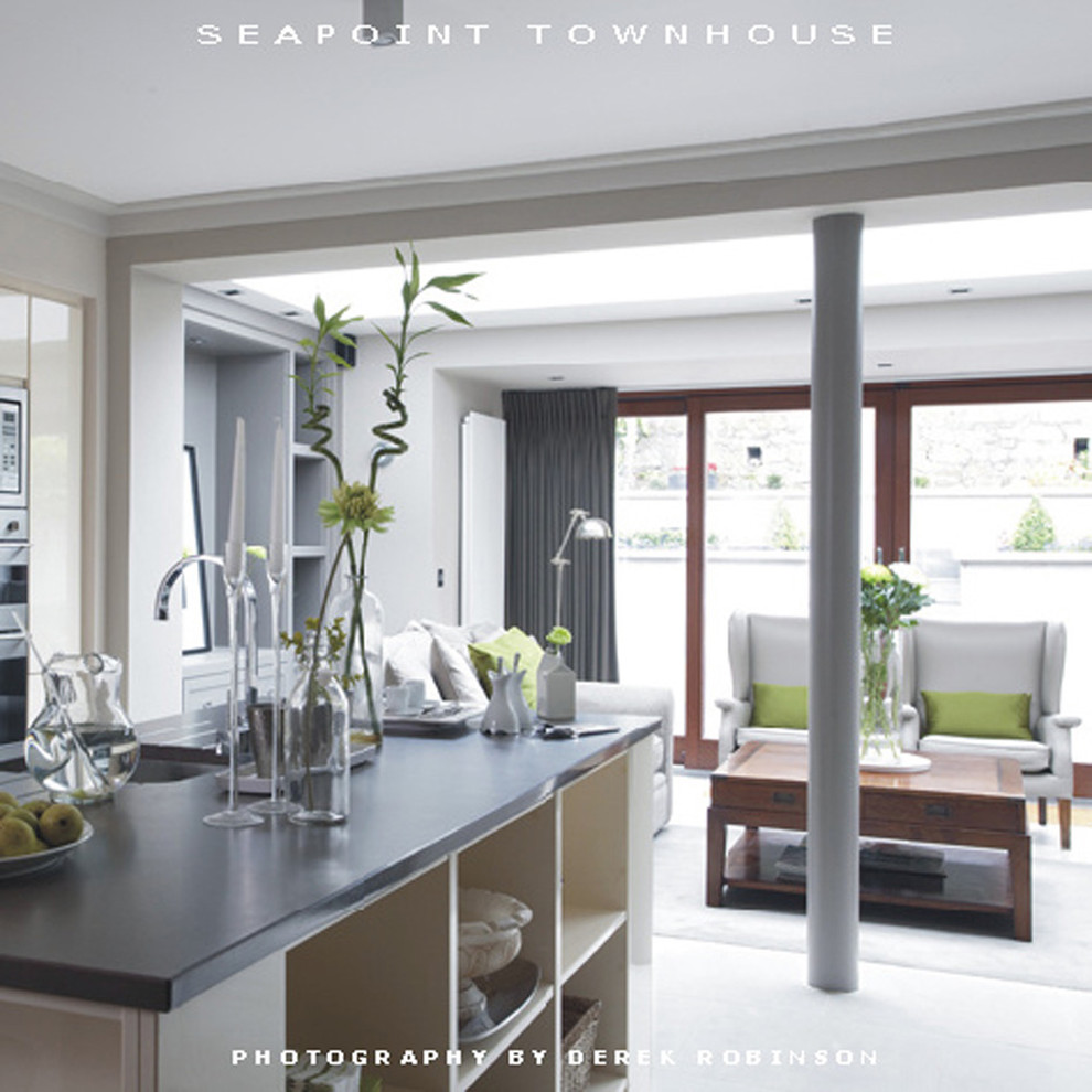 Contemporary single-wall open plan kitchen in Dublin with a single-bowl sink, flat-panel cabinets, grey cabinets, engineered stone countertops, black splashback, glass sheet splashback, stainless steel appliances, porcelain flooring and an island.