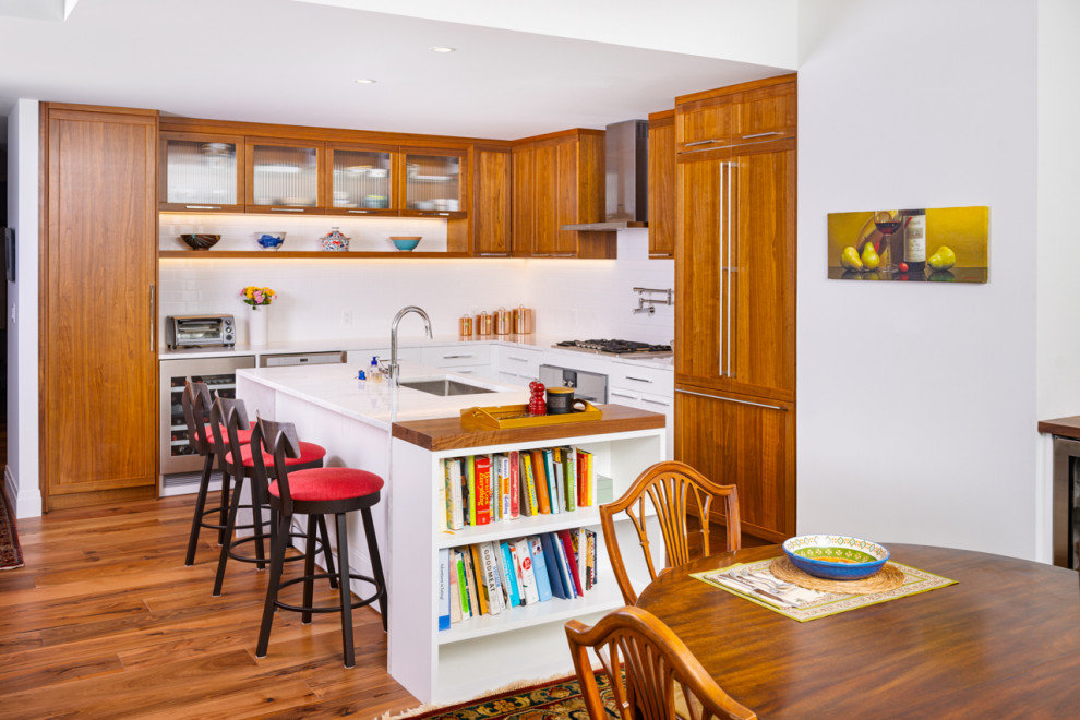 Klassische Küche in L-Form mit Unterbauwaschbecken, Schrankfronten im Shaker-Stil, hellbraunen Holzschränken, Elektrogeräten mit Frontblende, braunem Holzboden, Kücheninsel, braunem Boden und weißer Arbeitsplatte in Boston