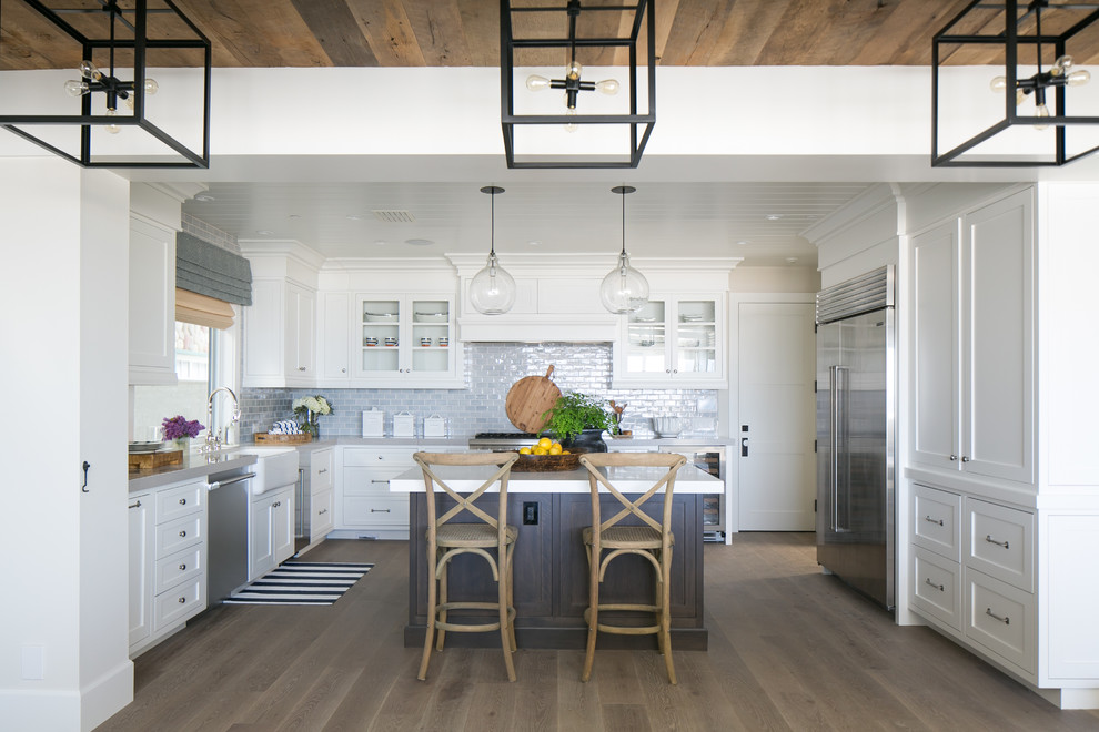 Example of a mid-sized beach style u-shaped dark wood floor open concept kitchen design in Orange County with a farmhouse sink, shaker cabinets, white cabinets, quartz countertops, blue backsplash, ceramic backsplash, stainless steel appliances and an island